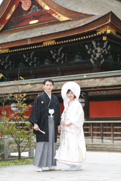 高級婚礼衣裳を取り扱う京鐘の衣裳のなかでも、北野天満宮での挙式でしか着ることができない神紋入りの特別な白無垢と紋服を選んだふたり。
神紋「星梅鉢紋」の白無垢は、正絹の光沢がはんなりとした印象をあたえ、粗伏織で織られた柄が美しく浮かび上がる最高級の逸品。
新郎の紋付は、三種の紋を黒の漆箔押しで織り上げたもの。品格ある漆の輝きが美しい逸品です。