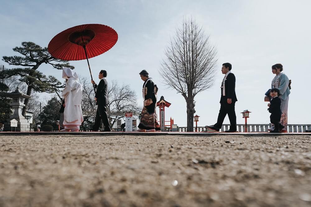 結婚式は和装で挙げたいとずっと思っていた新婦。希望は、大切な家族に見守られて式を挙げること。コロナ禍でも「親に負担が掛からず、安心して過ごしてもらえる」ことを優先して、新郎の実家がある栃木県で挙式をすることに。下見で参拝に行った「足利織姫神社」は見晴らしの良い高台にあって、青空に映える朱の社殿に思わず一目惚れ。「ここで白無垢姿を見たい」と言ってくれた新郎の気持ちが背中を押すことに。婚礼衣裳は日本の伝統を大切に、文様の意味にもこだわって選んだ白無垢と紋服。「『天赦日』と『一粒万倍日』が重なる、とてもおめでたいお日柄にもこだわって、両家の家族8名でのアットホームな和婚を実現。
