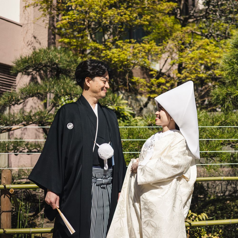 ゲストがアクセスしやすい立地と、「伊勢神宮」の御祭神をお祀りする「東京大神宮」に縁を感じ、ここでの挙式を決めたふたり。日本の伝統を大切にしながら、家族みんなが楽しめる結婚式を準備した。「東京大神宮」は日本で初めて神前結婚式を行った由緒ある神社。憧れの白無垢をまとい、古くから伝わる儀式や所作の一つひとつが美しく、自然と背筋が伸びたという。披露宴は隣接する会場へ。陽光が降り注ぐシックな空間を、温かみのある春らしい装飾に。カーネーションやガーベラなど、優しい色合い花々でアットホームな雰囲気を演出した。おもてなしの料理は、幅広い年代のゲストが食べやすい和洋折衷会席。和と洋が楽しめるボリューム満点のメニューも好評だった。また一番のお気に入りは「東京大神宮」らしい王道の家族写真。ここで過ごした家族や親族との幸せな時間が、写真に映るみんなの笑顔を見るたびに鮮明に甦る。
