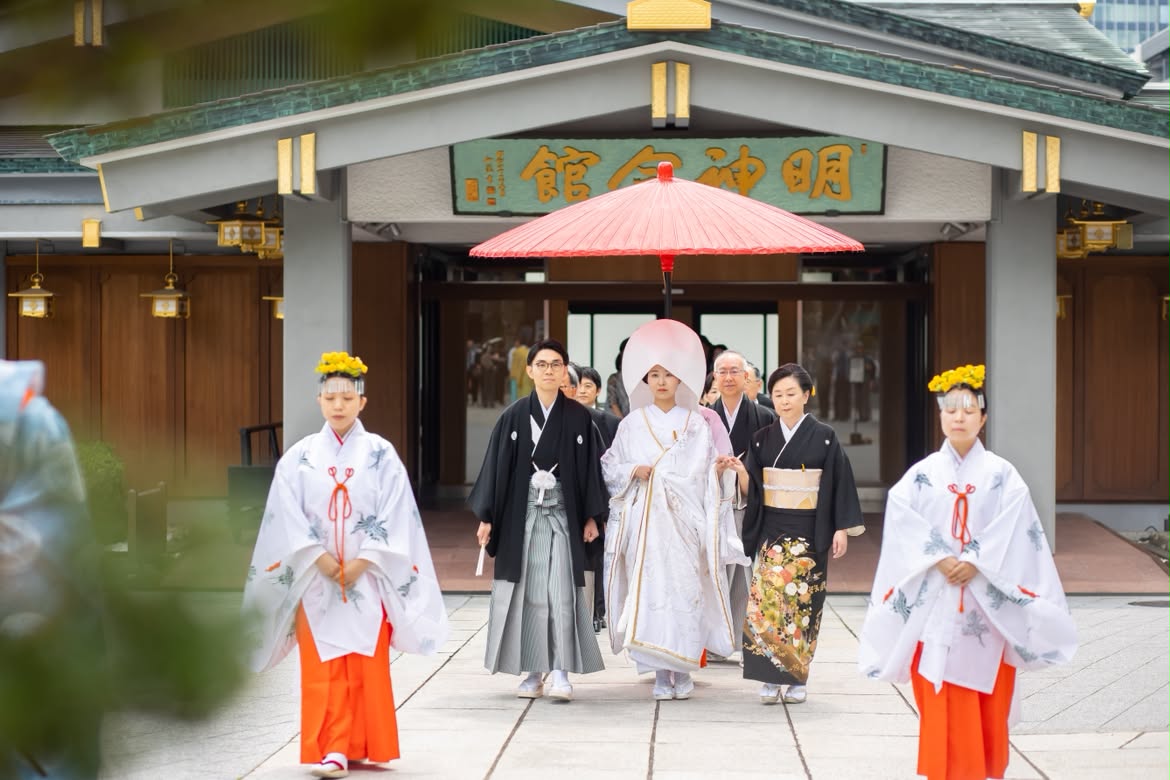 芽の輪くぐりで無病息災を祈願する、夏越大祓式が執り行われる6月の神田明神。憧れていた白無垢と綿帽子姿で臨んだ神前式は、茅の輪をくぐるこの時期だけの特別な参進から。伝統美に満ちた厳かな社殿での儀式は格式高くも温かく、ひとつの節目と新しい門出を強く感じられた。披露宴会場は水色のテーブルクロスにオレンジ色のアイテムを効かせて季節感を演出。食事は出汁で食べる肉料理など、ふたりもお気に入りの和洋折衷料理。和と洋が融合したおもてなしは気負わずリラックスして過ごせたとゲストからも大好評。さらにドレスでバージンロード風の再入場や、ケーキカットなどを取り入れた洋風の演出はサプライズ感があり、今まで参列した式のなかで一番楽しかったとのうれしい声も。挙式では新郎母が手作りしたリングピロー、ドレスには母と新郎と一緒に作成したブーケを合わせ、家族からの祝福と絆を深めた心温まる結婚式を叶えた。
